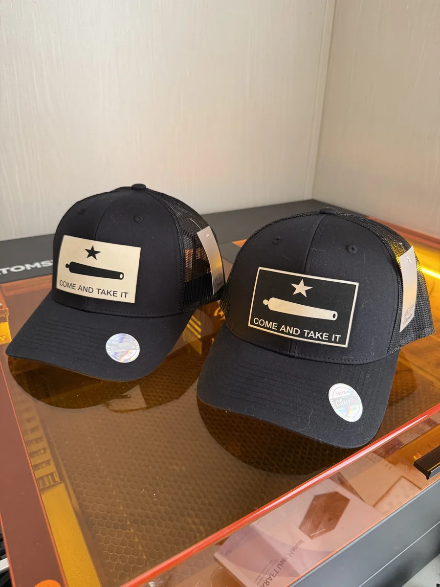 Pair of black caps with Come and Take It flag patches, including one reverse-engraved design