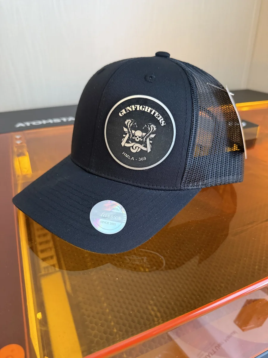 Black cap with an engraved HMLA-369 Gunfighters squadron logo patch